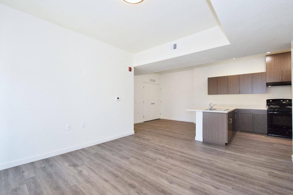 an empty living room and kitchen with white walls and wood flooring
