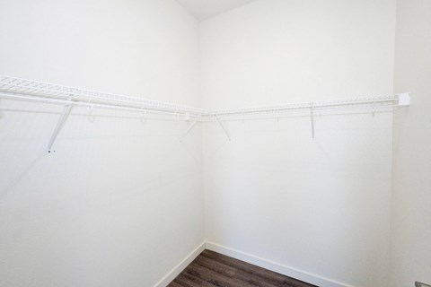 an empty closet with white walls and shelves and a wood floor