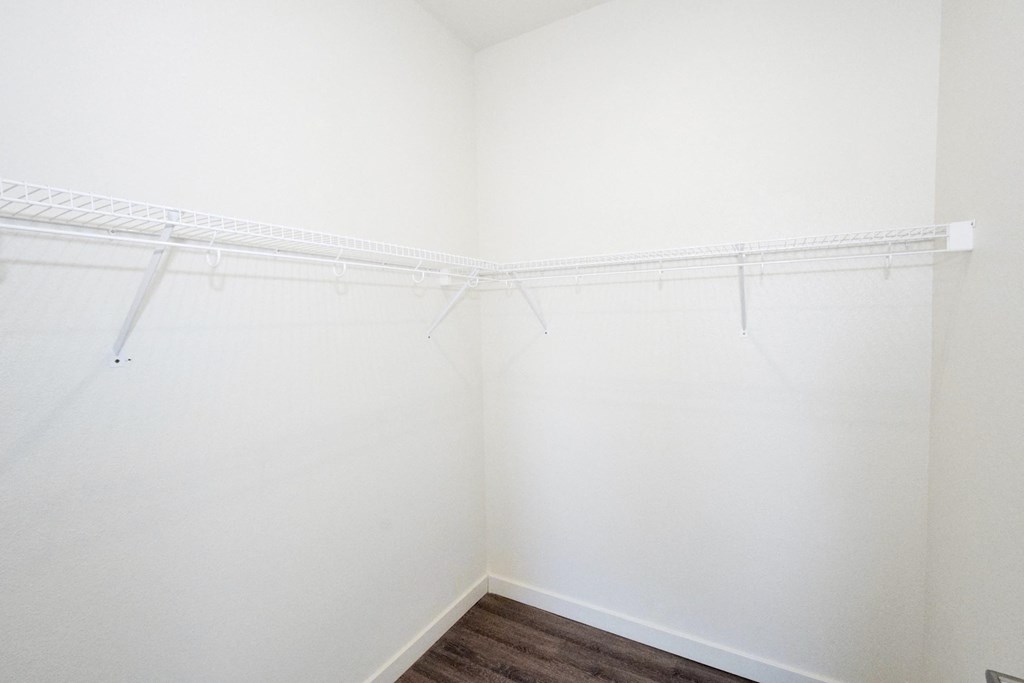 an empty closet with white walls and shelves and a wood floor