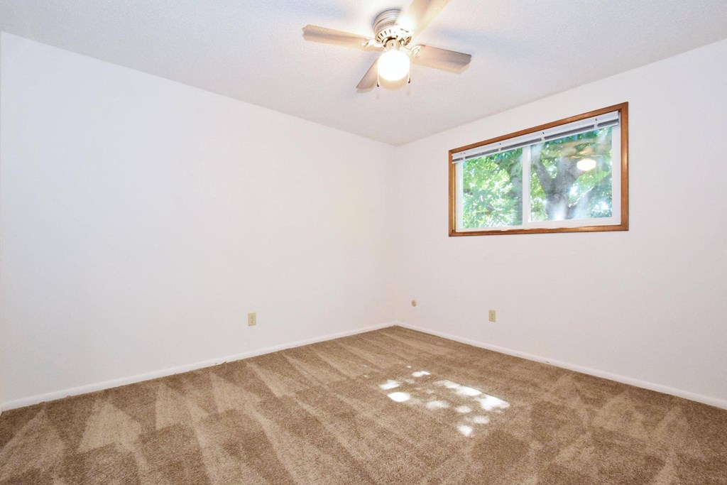 an empty room with a ceiling fan and a window