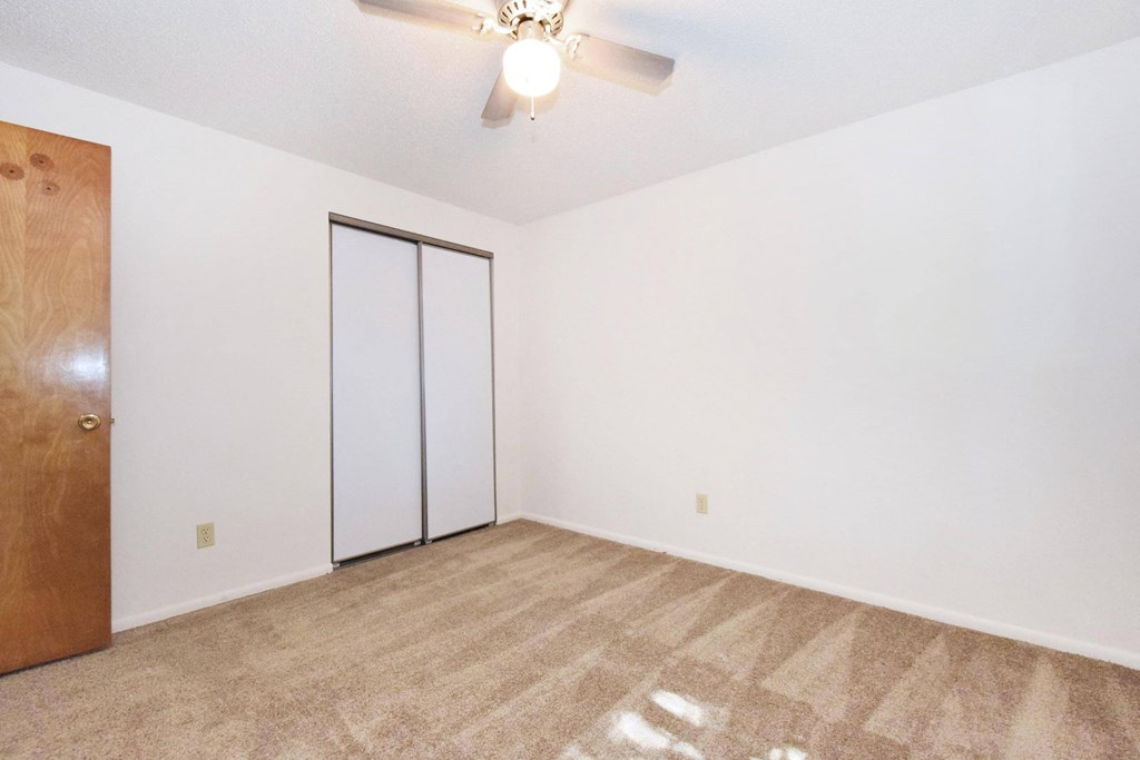 a bedroom with white walls and a ceiling fan
