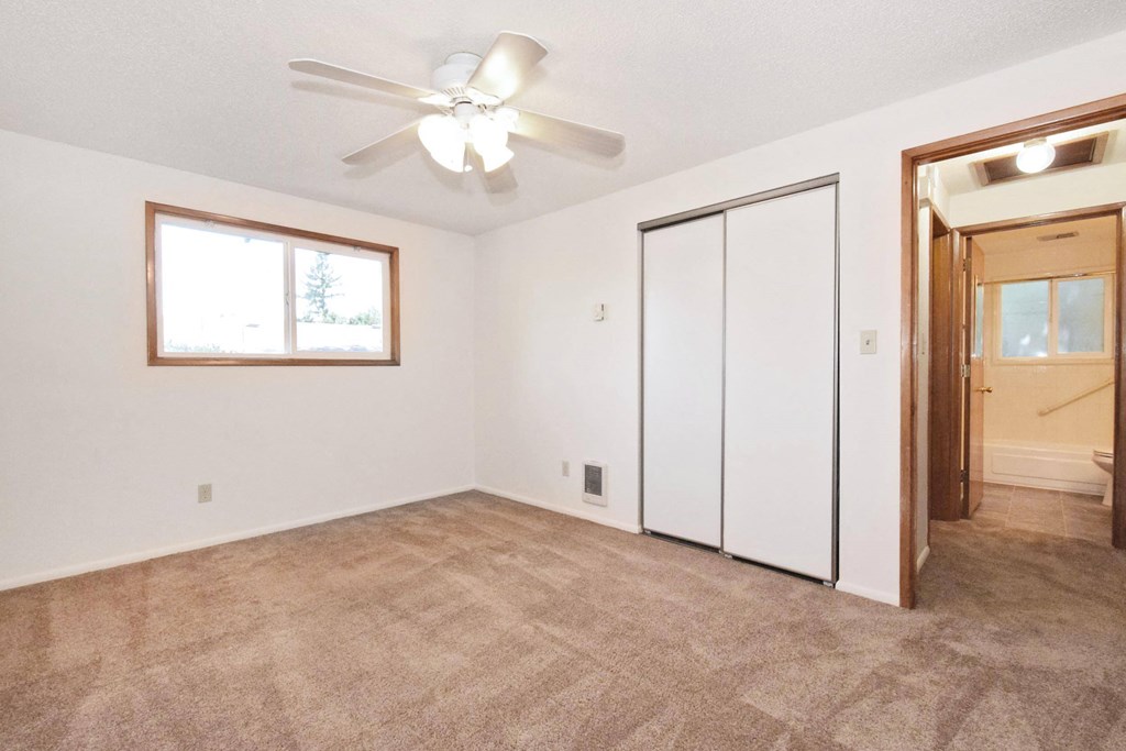 an empty bedroom with a ceiling fan and a closet