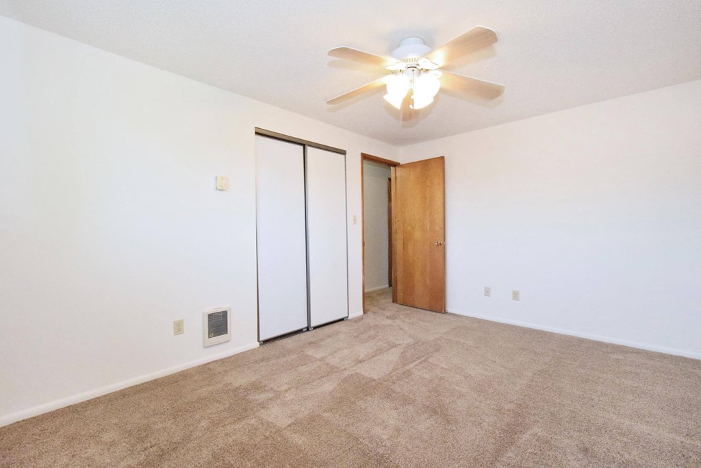 a bedroom with white walls and a ceiling fan