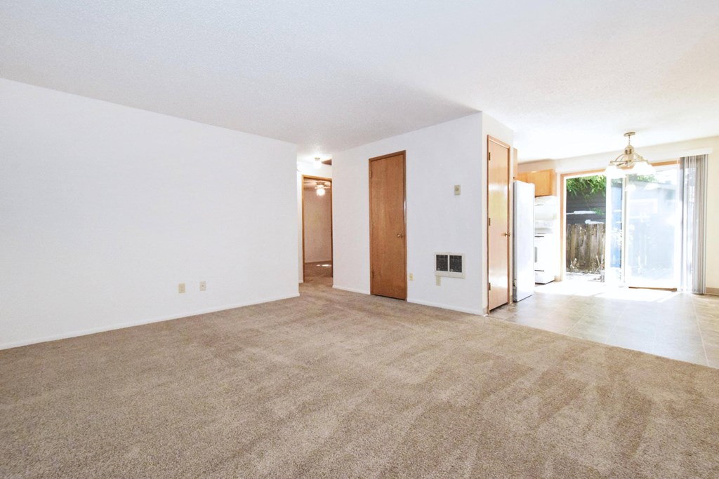 an empty living room with white walls and a beige carpet
