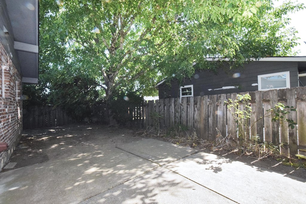 a house with a fence and a tree in front of it