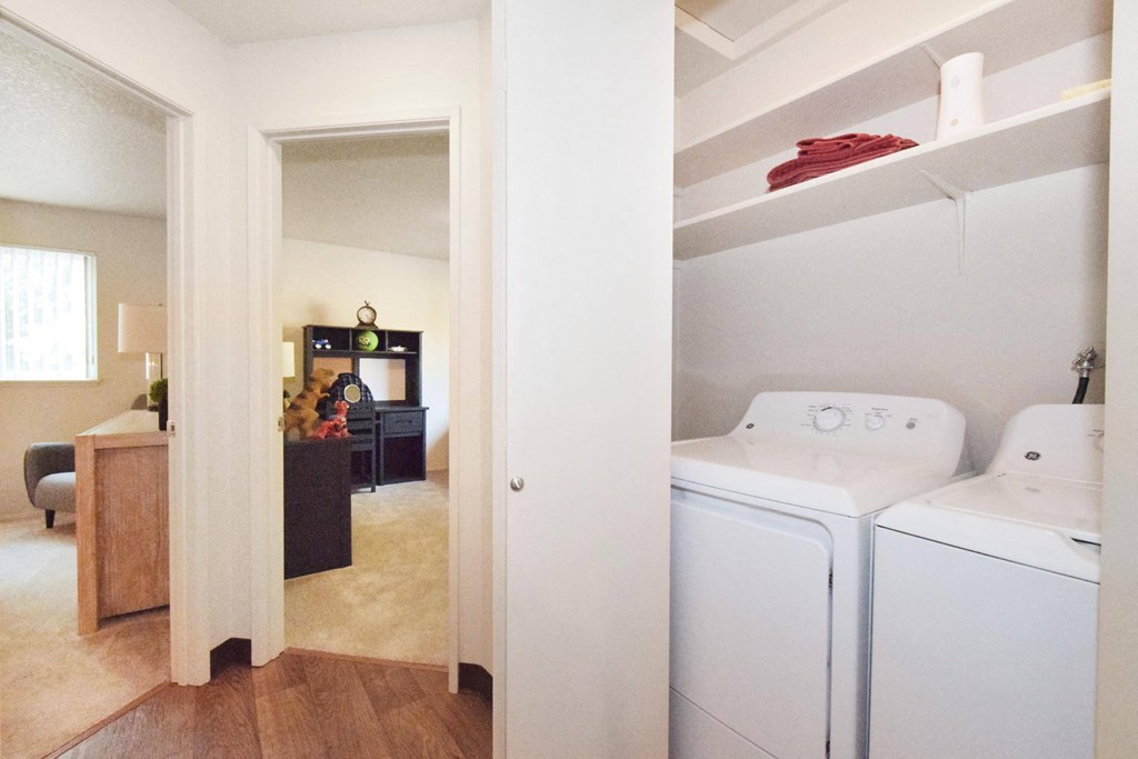 a washer and dryer in a room with a desk and a living room in the