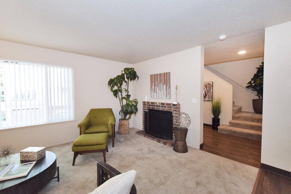 a living room with a fireplace and a staircase in the background