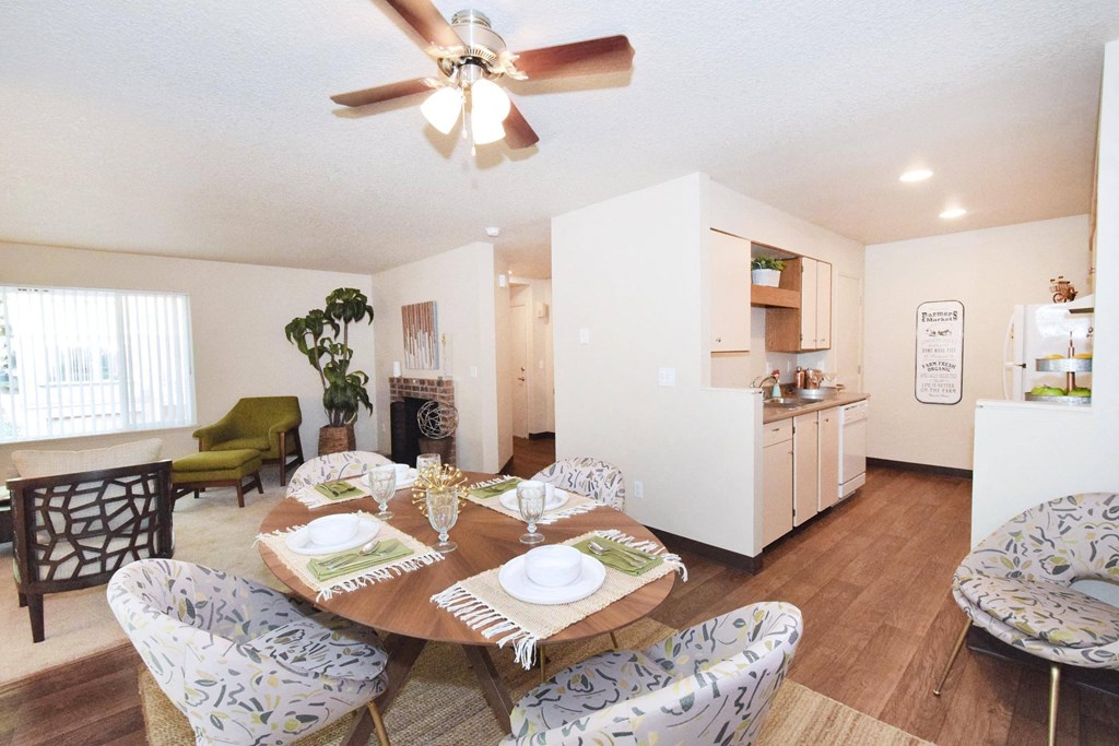 a dining room with a table and chairs and a kitchen in the background
