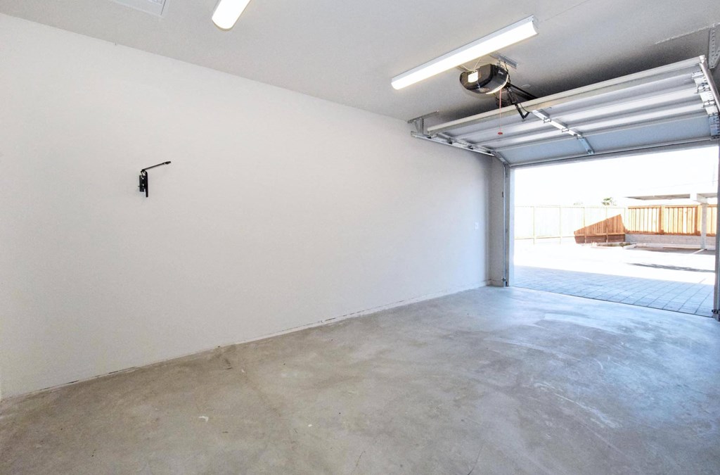 the interior of a garage with white walls and a door that leads to a deck