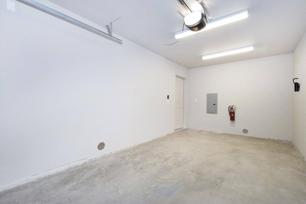 a large empty room with white walls and a red fire hydrant in the corner