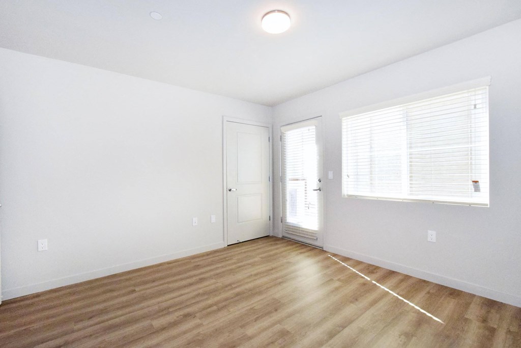 a bedroom with hardwood floors and white walls