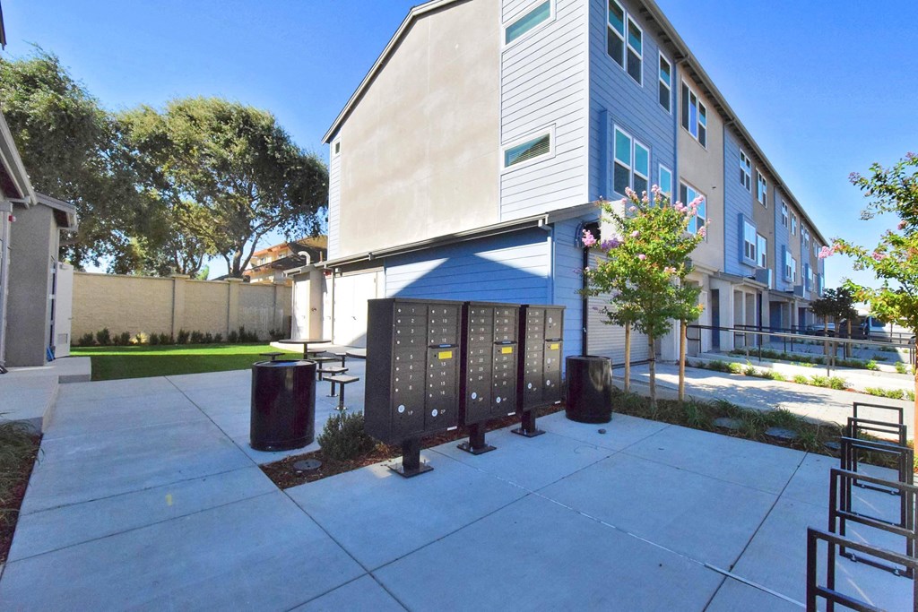 a blue and white building with a sidewalk and trash cans in front of it