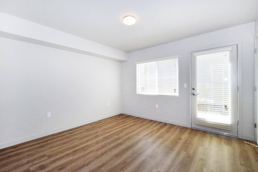 a bedroom with hardwood floors and a door to a balcony
