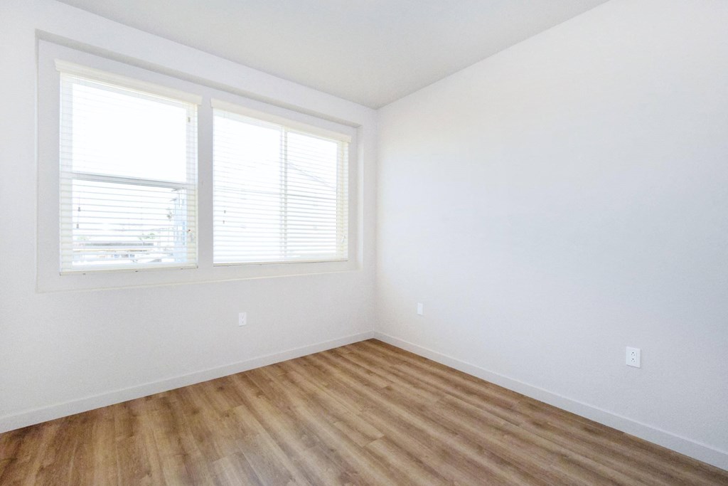 an empty room with white walls and wood floors