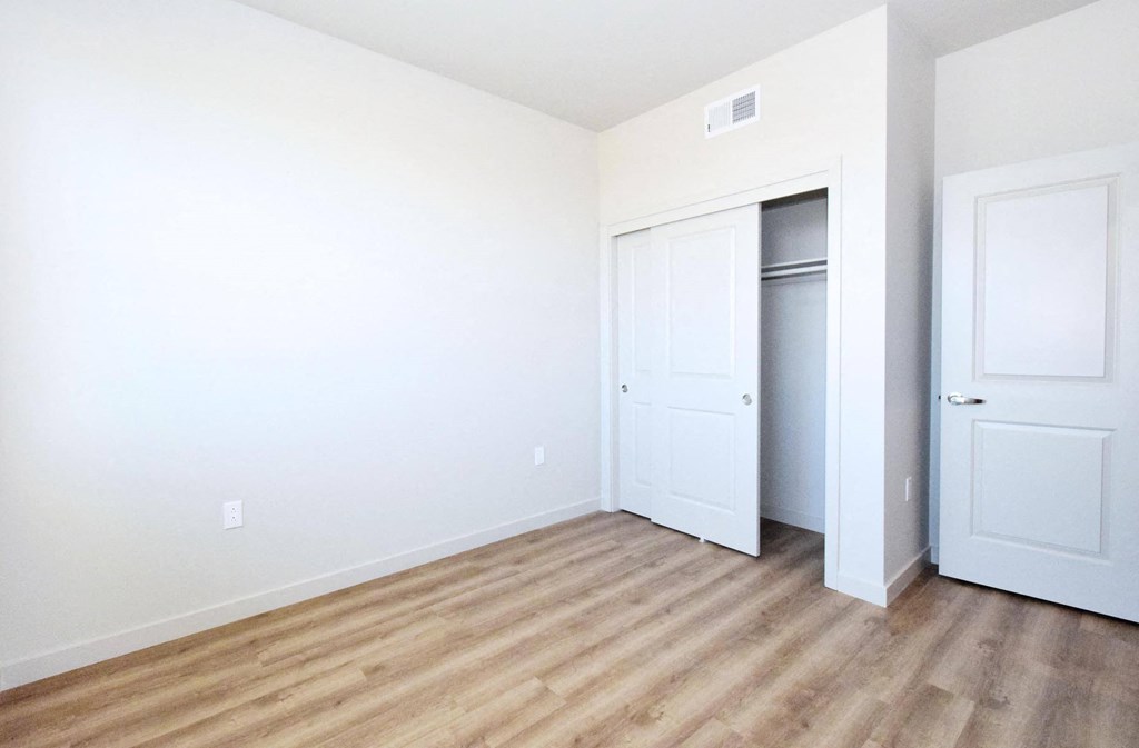 a bedroom with white walls and hardwood floors