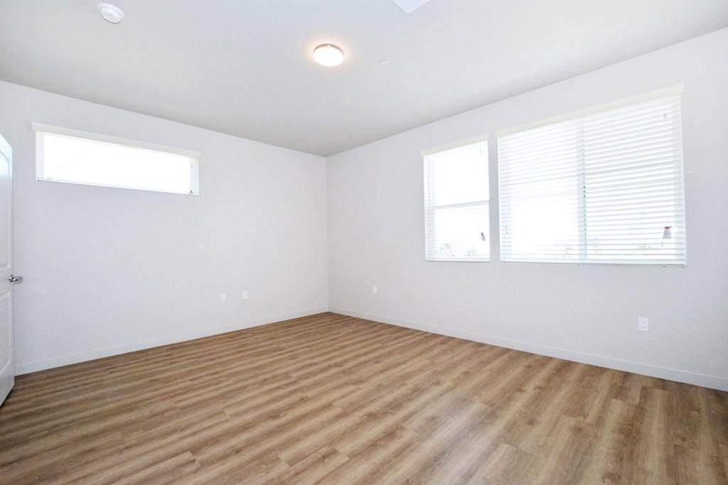 a bedroom with a hardwood floor and three windows