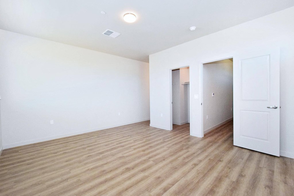 a bedroom with hardwood floors and white walls