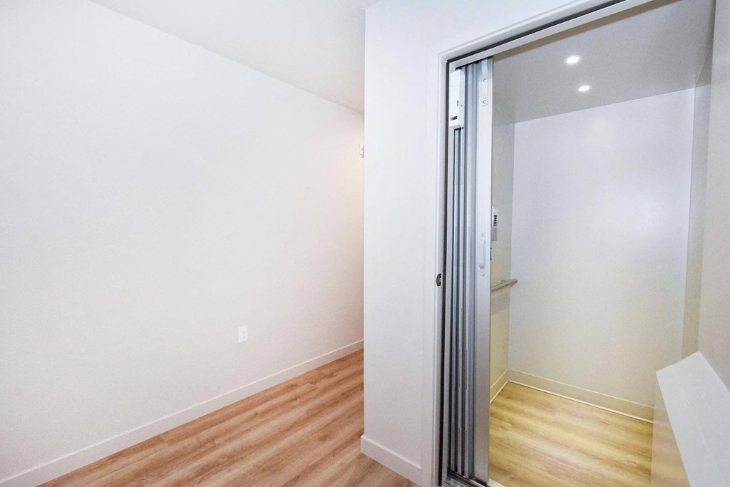a bedroom with white walls and hardwood floors