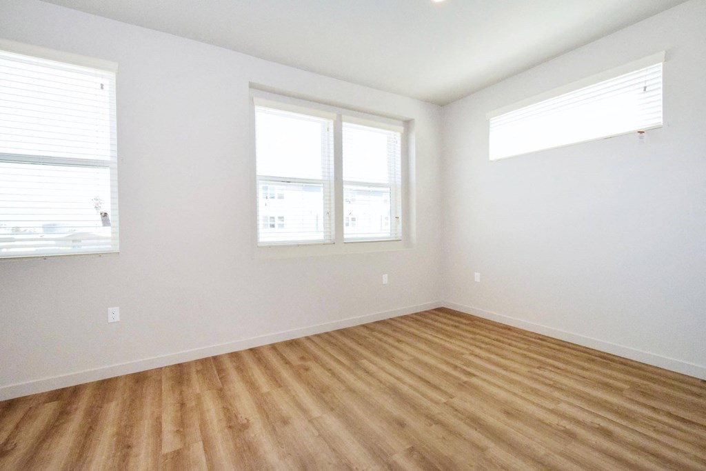 an empty room with three windows and a wooden floor