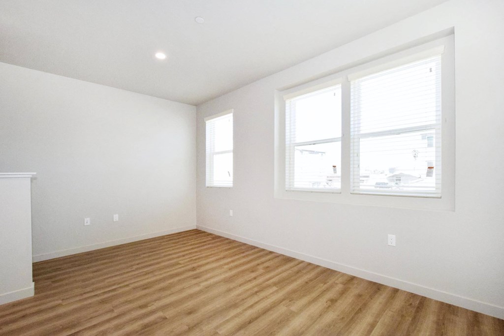 a bedroom with a hardwood floor and three windows