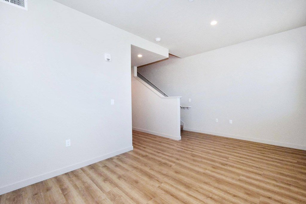 an empty living room with white walls and hardwood floors