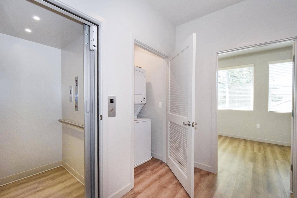 a bedroom with a medium hardwood floor and a closet with a washer and dryer