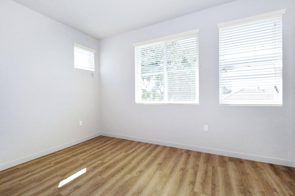 an empty room with a hardwood floor and three windows
