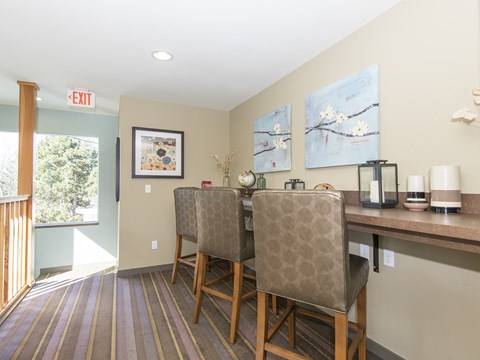 a dining area with two chairs and a bar with a counter and a window