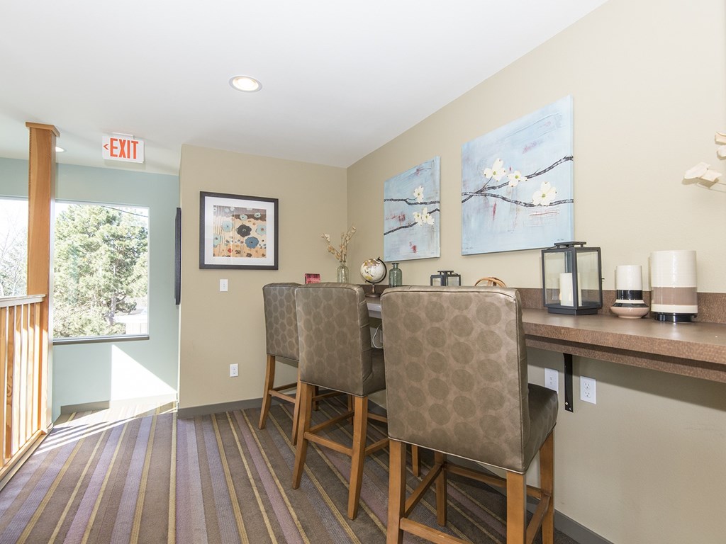 a dining area with two chairs and a bar with a counter and a window