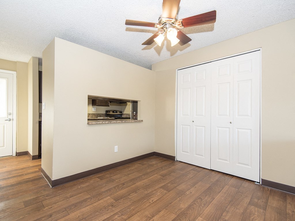 an empty living room with a ceiling fan and a closet