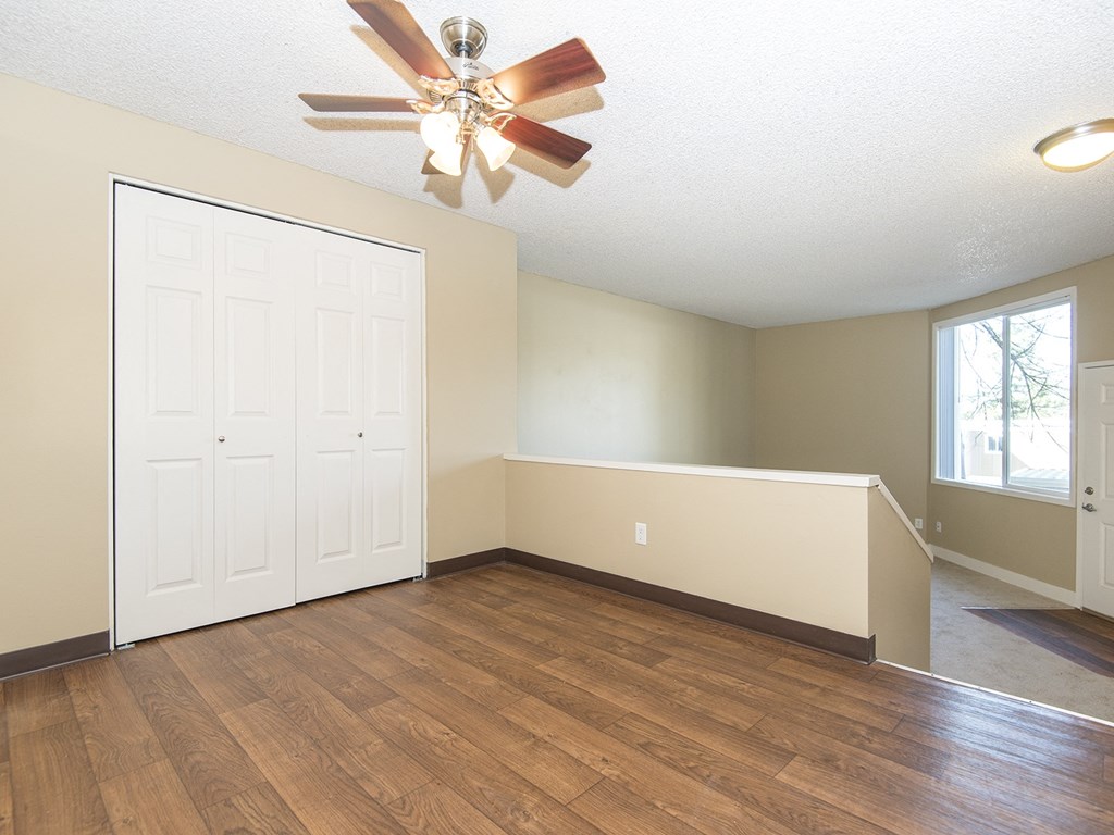 an empty living room with wood floors and a ceiling fan