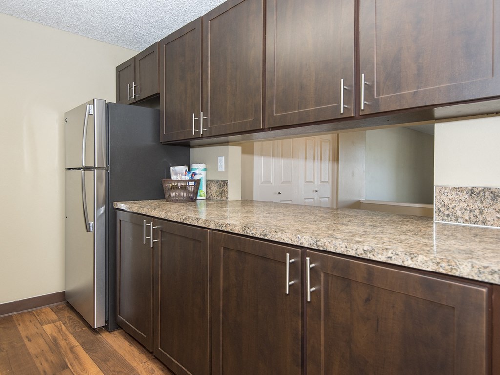a kitchen with wooden cabinets and a granite counter top and a refrigerator