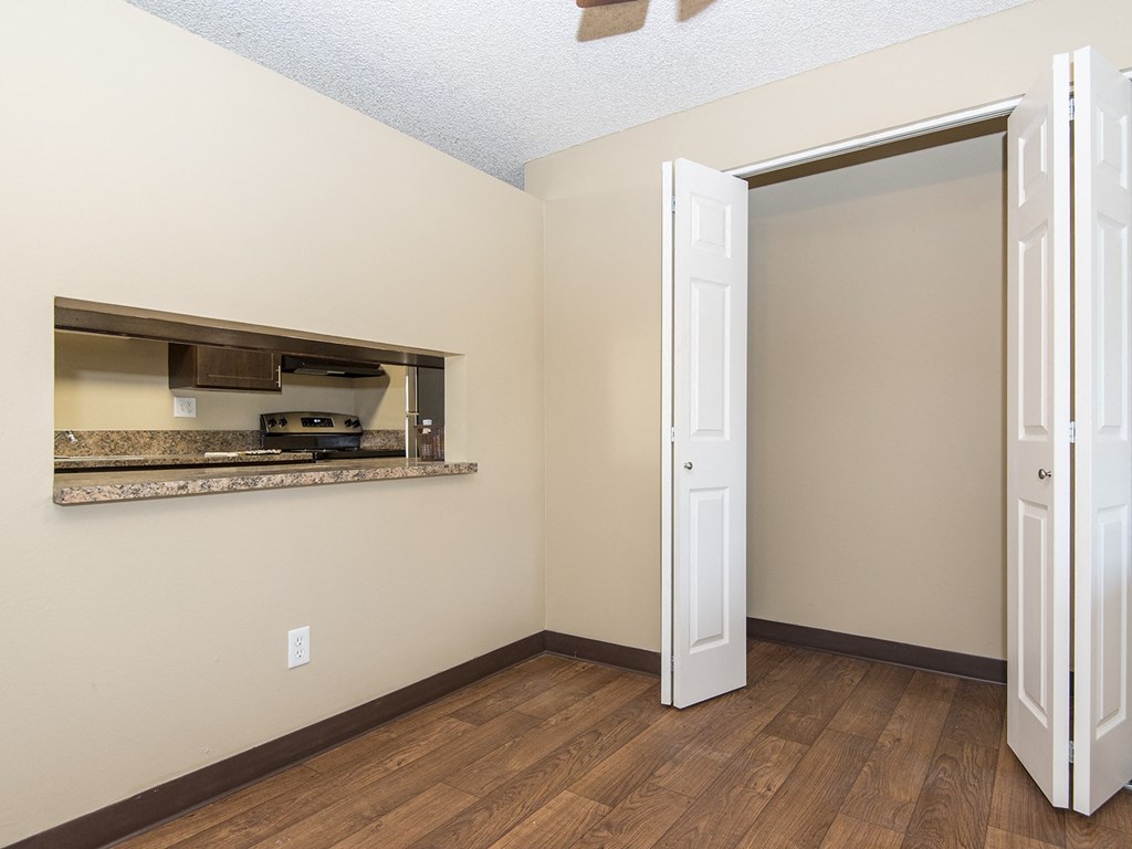 an empty room with a door to the kitchen and a mirror on the wall