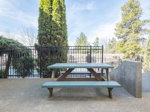 a picnic table in a park with a fence and trees