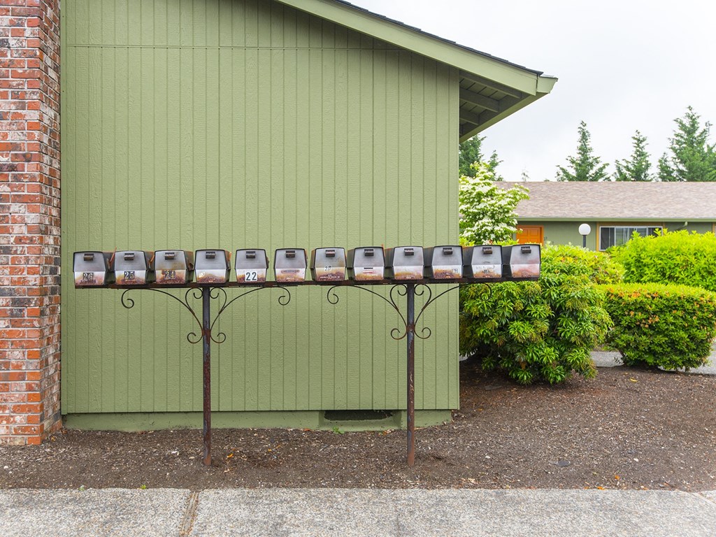 a mailboxalogger in front of a green building with trees and bushes