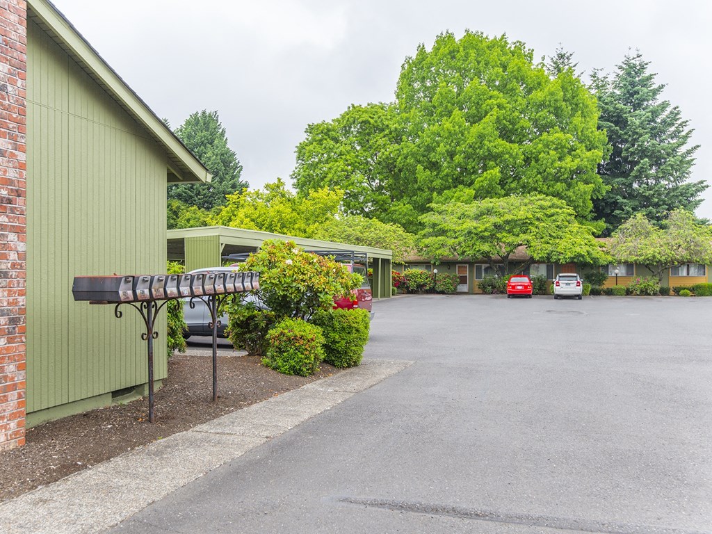 a parking lot in front of a green building with a mailbox