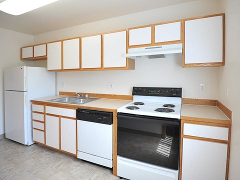 an empty kitchen with white appliances and wooden cabinets