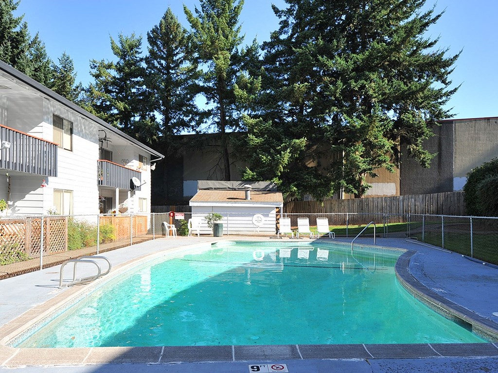 a swimming pool in front of a house with trees