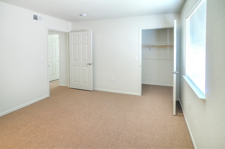 an empty bedroom with a closet and a window
