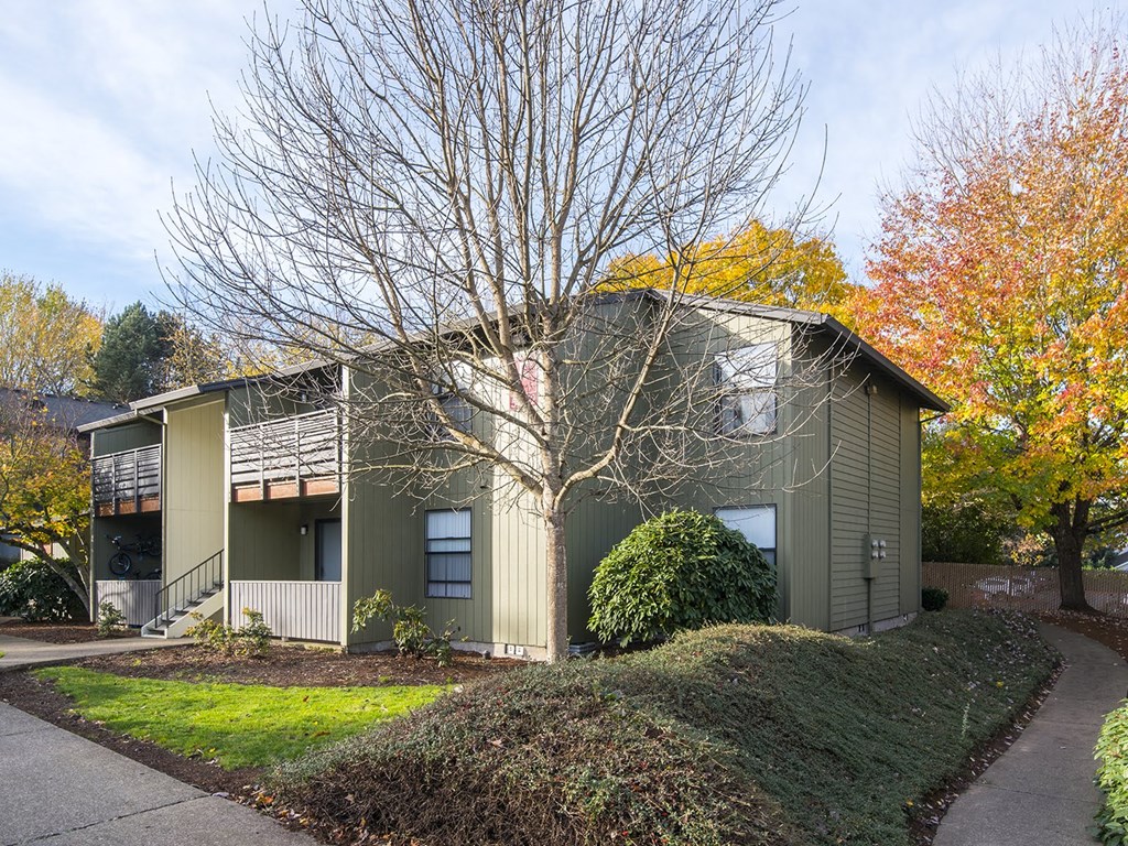 a green house with a tree in front of it