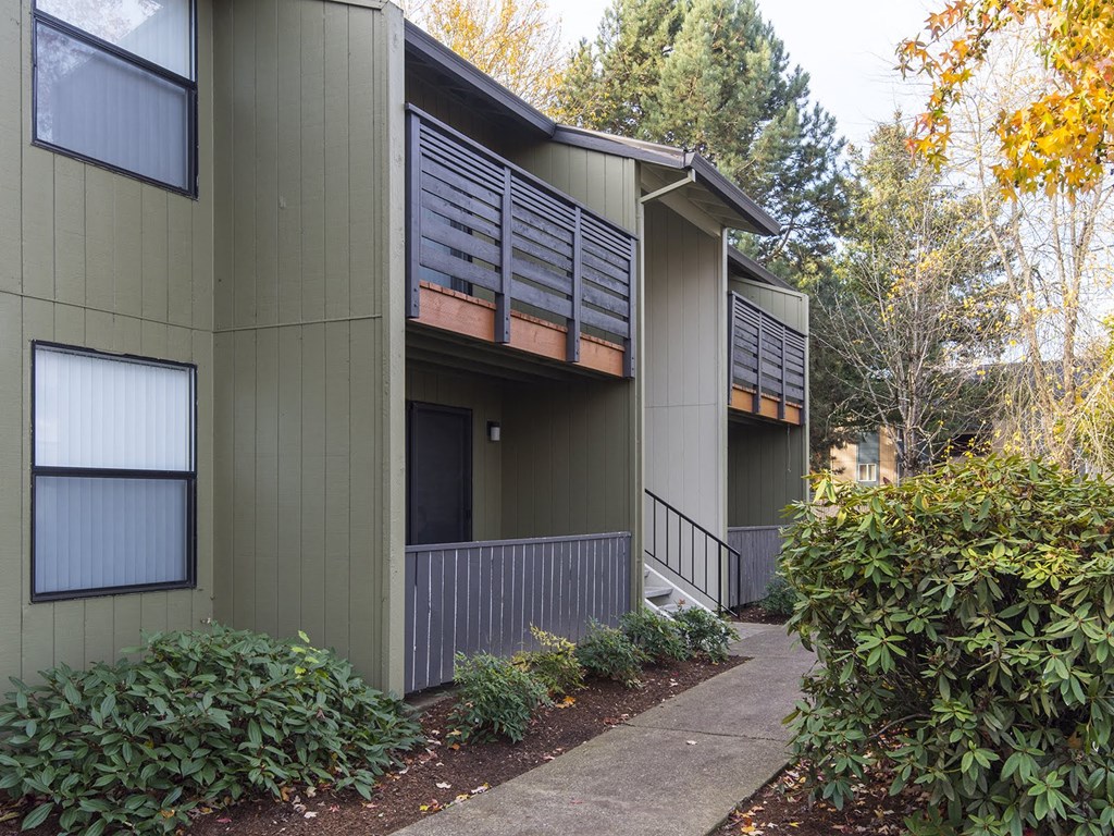 a green building with a sidewalk in front of it