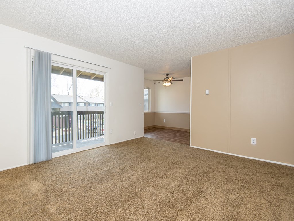 an empty living room with a window and a ceiling fan