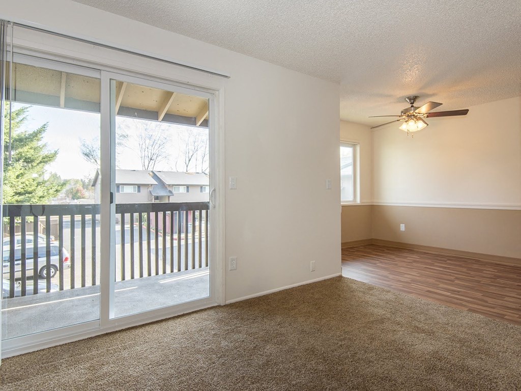 a living room with a large window and a ceiling fan