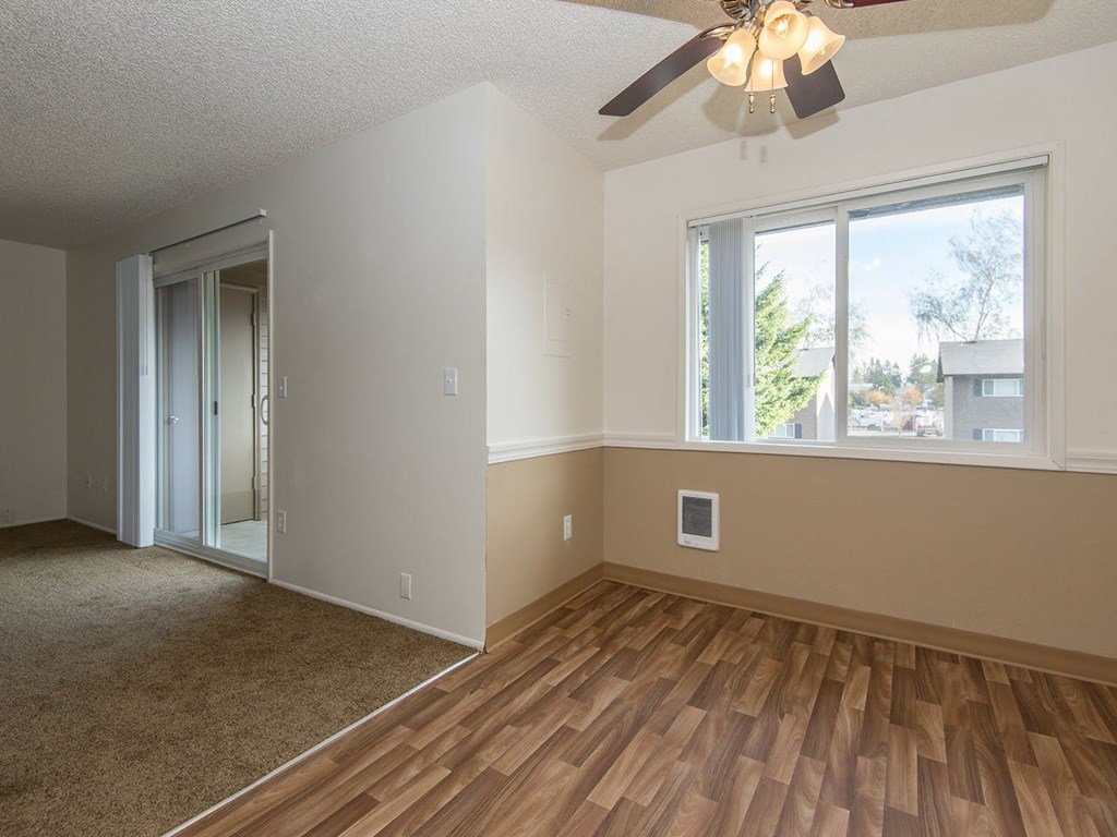 an empty living room with a ceiling fan and a window