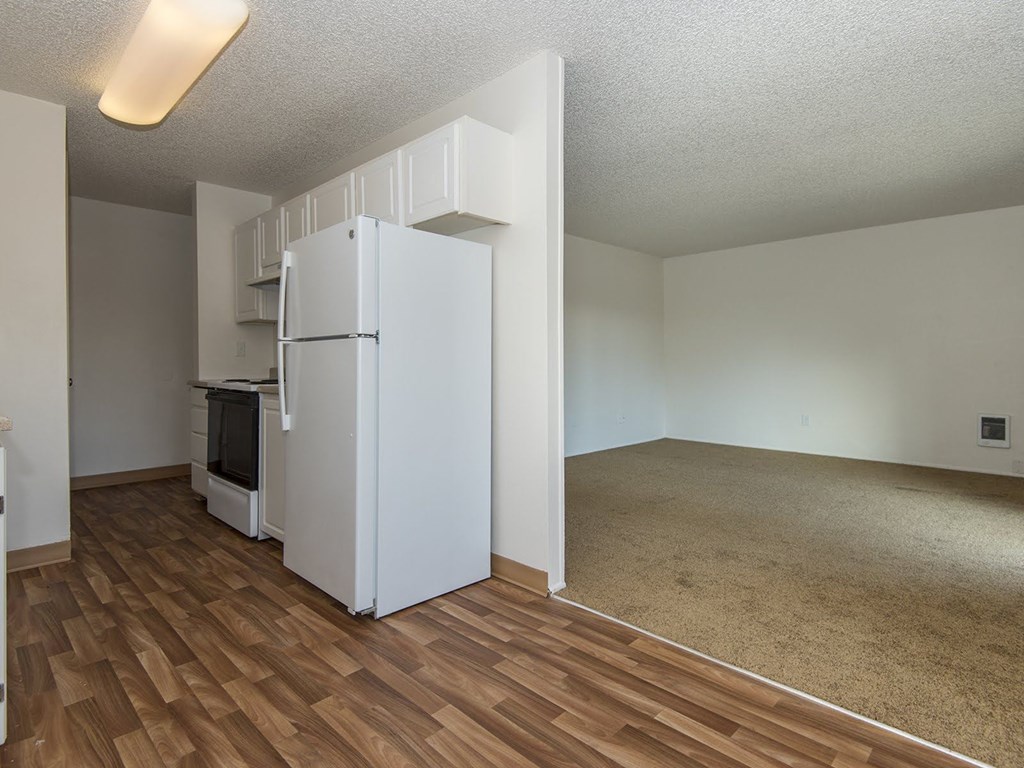 an empty living room and kitchen with a refrigerator