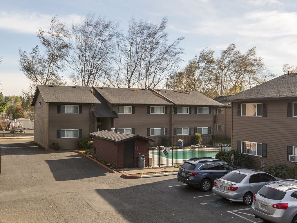an apartment building with cars parked in a parking lot