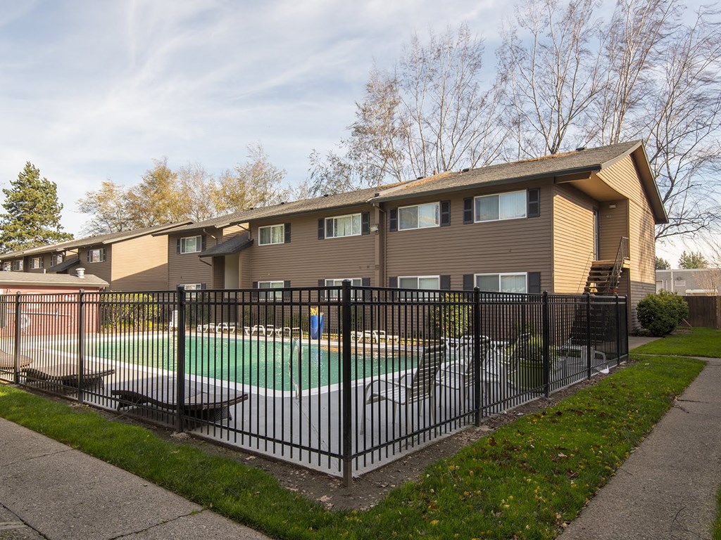the backyard of a house with a pool behind a fence
