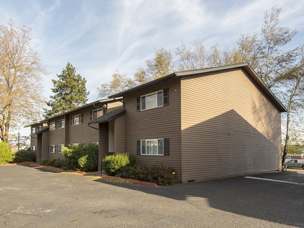 the front of a brown house with a parking lot