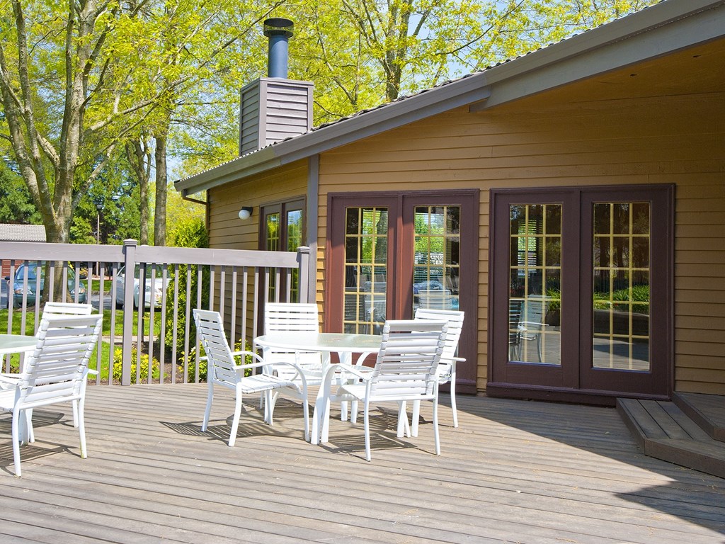 a patio with chairs and a table on a wooden deck