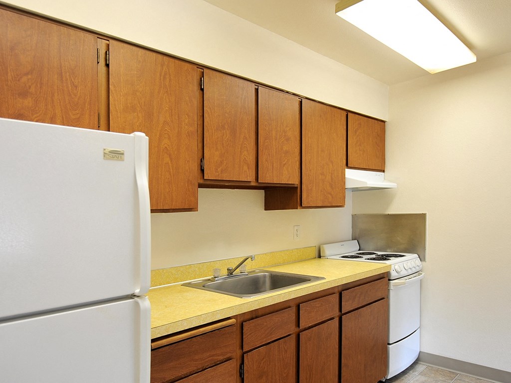 a kitchen with white appliances and wooden cabinets and a refrigerator